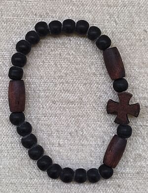 PULSERA ELÁSTICA MADERA 6MM NEGRA CON 3 TUBOS ALARGADOS Y CRUZ DOS TONOS