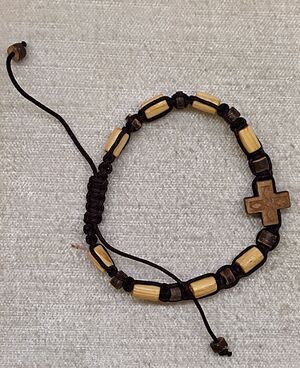 PULSERA CUERDA MADERA CLARA 6 MM TUBOS ALARGADOS Y CRUZ GRABADA